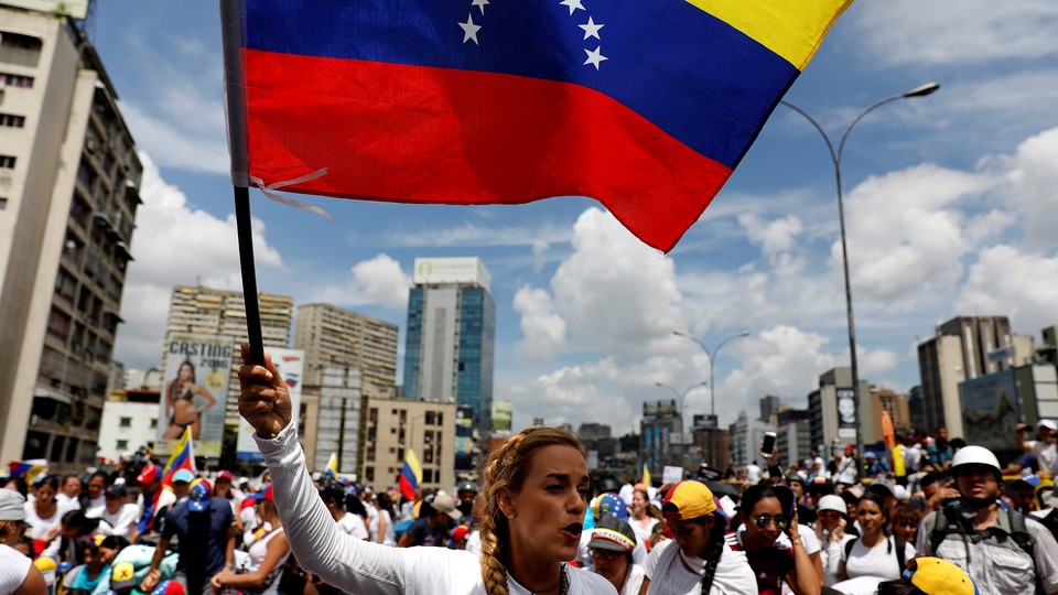 Lilian Tintori waves a Venezuelan flag amid a group of female protesters.