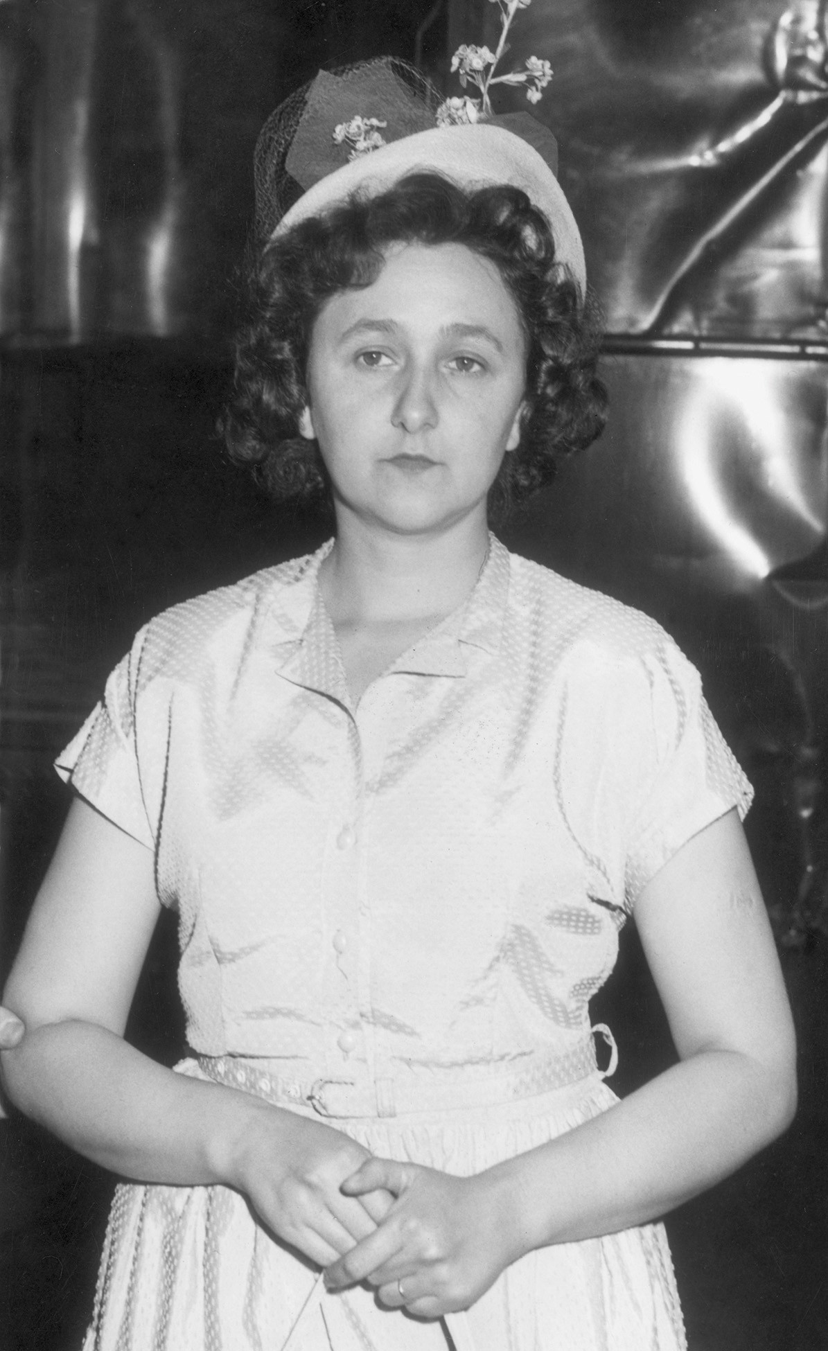 black-and-white archival photo of woman with curly hair in white hat with flowers and pale dress