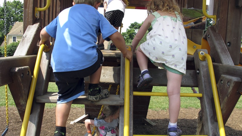 A boy and girl climb up a swing set.