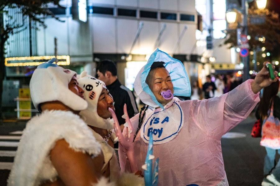 Several people in childlike costumes pose for a selfie in a crowded street.