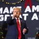 Trump on a Christmas-decorated "Make America Great Again" podium, pointing at the camera
