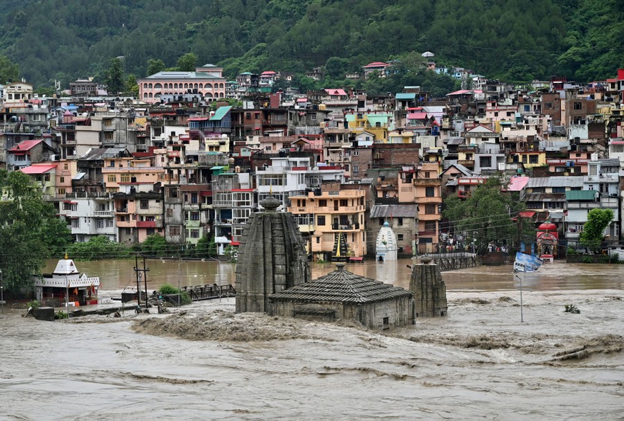 Fast-flowing floodwater surrounds a temple near a riverside town.