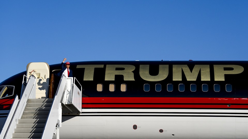 Trump waves standing next to his private plane that reads: TRUMP