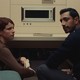 Jessie Buckley and Riz Ahmed sitting together in a retro room