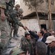 A soldier reaching down to shake President Assad's hand