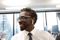 A man wearing Apple AirPod headphones smiles in an office