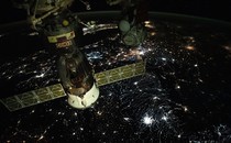 A night view of the Soyuz module docked with the ISS as it passes above Eastern Europe, showing many different-colored city lights