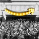 An old-timey crowd floods into a store with a giant Amazon logo superimposed on it.