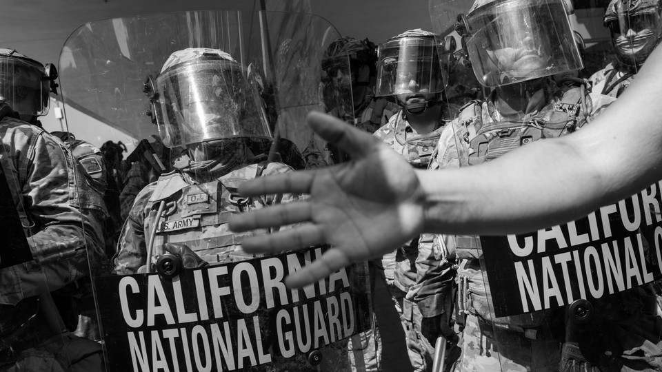 A photograph of the California National Guard, with a hand reaching in front of the camera lens