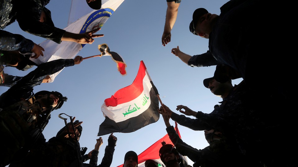 Circle of Iraqi soldiers celebrate as they waive an Iraqi flag.