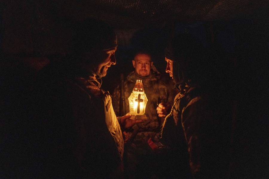 Three soldiers hold a small lantern with a cross on it.