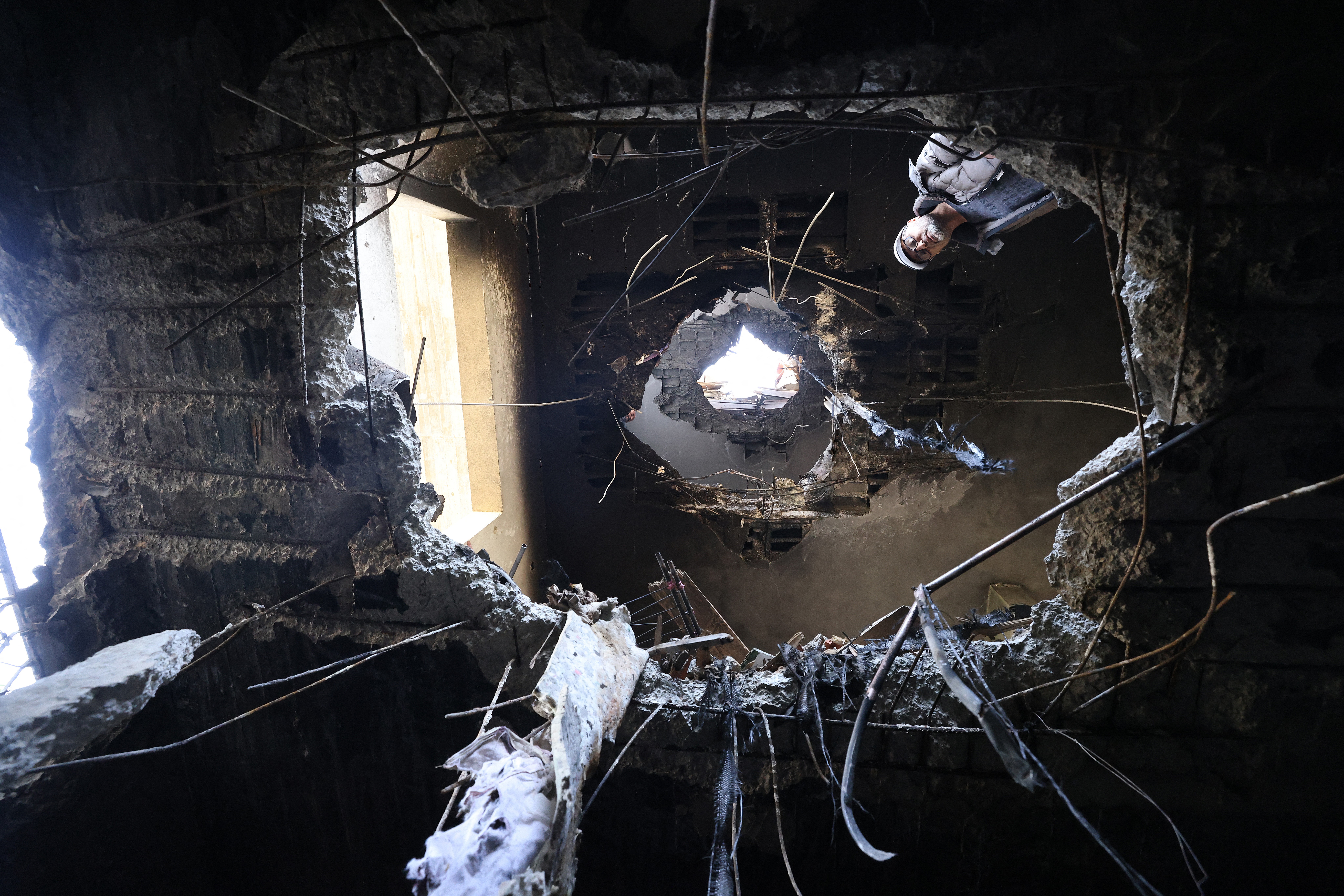 A man looks at damage caused by fragments of an intercepted Iranian rocket, which appears to have punched a large hole through at least three floors. 