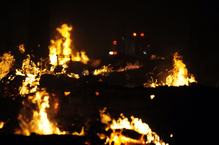 Fires burn across a forested area at night.