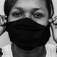 Black-and-white close-up of a woman putting on a face mask
