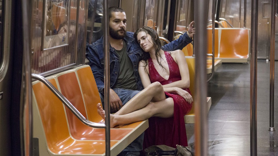 Marnie wears a red dress and leans on Charlie's shoulder in a subway