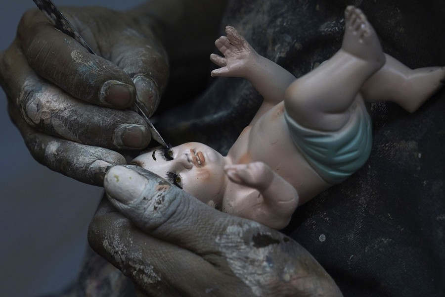 A man repairs a baby-Jesus figurine.