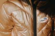 An "I Voted" sticker on a golden puffer jacket