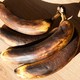 Four very brown bananas laid on their side on a wood surface