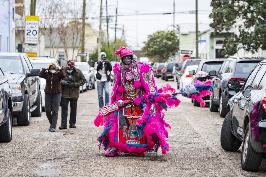 A performer in bright clothing walks down the middle of a street in New Orleans.