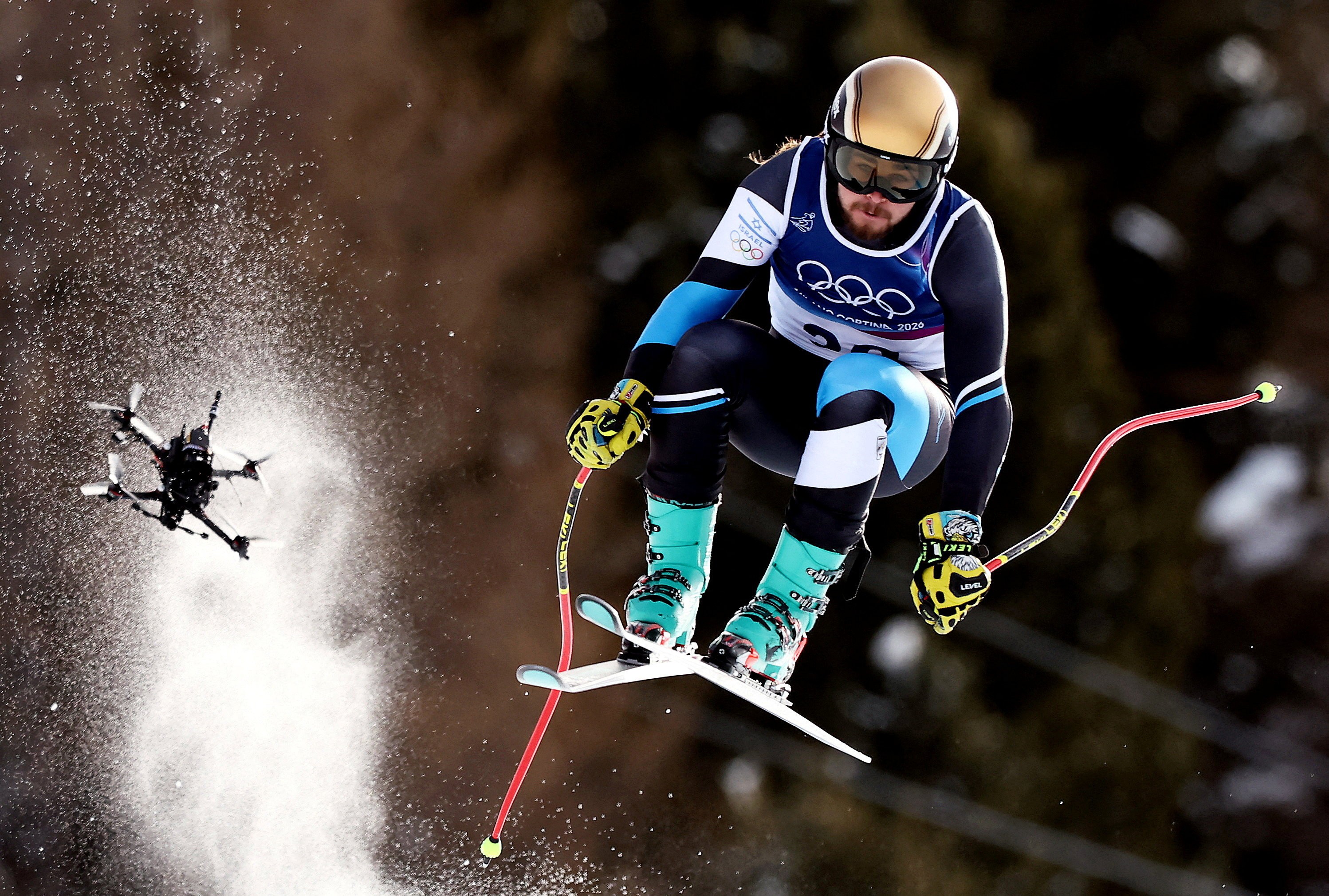A skier catches some air during a downhill race, followed closely by a camera drone.