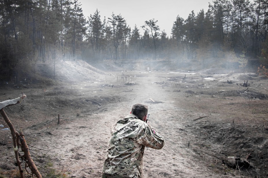 a man in fatigues practices shooting targets in a field