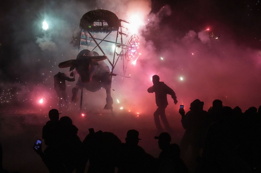 People watch as fireworks are used to set fire to a bull sculpture.