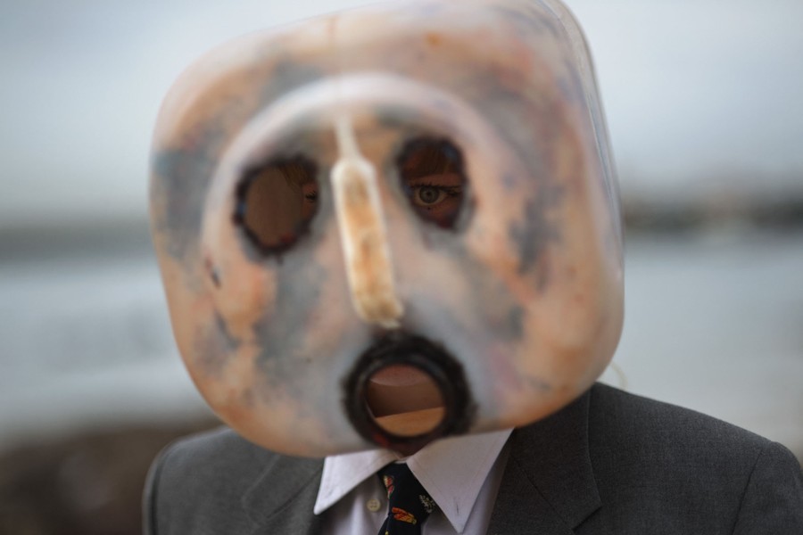 A protester wears a suit and a plastic-oil-container mask with holes cut into it for eyes.