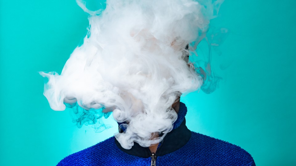 A person's face is obscured by a cloud of vapor.