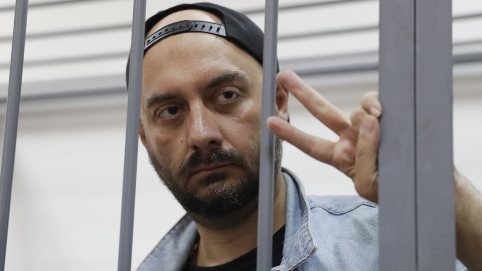 Serebrennikov makes a peace sign as he stands behind bars at a Moscow court hearing in September 2017.