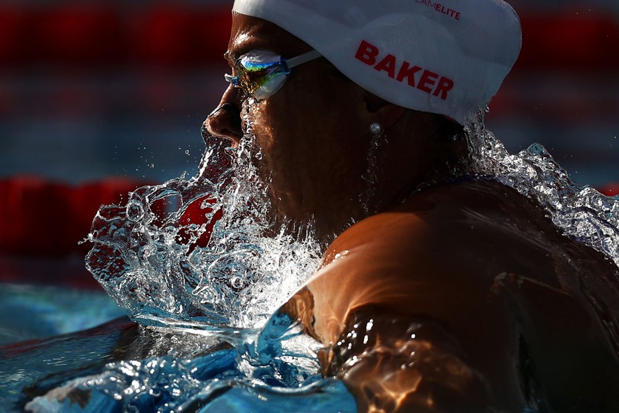 A swimmer splashes as they break the surface during a race.