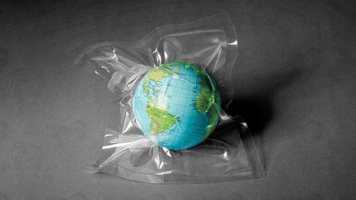A toy globe inside a plastic shrink wrap bag on a gray floor