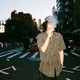 A color photograph of a man vaping on the street.