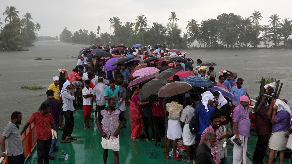 Volunteers stand under umbrellas on a boat that takes them to visit a flooded area in Kerala.