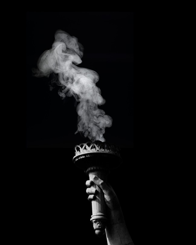 Black-and-white image of smoke rising from the Statue of Liberty's snuffed-out torch