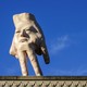 A 16-foot-tall sculpture shaped like a human hand with a face stands on a rooftop.