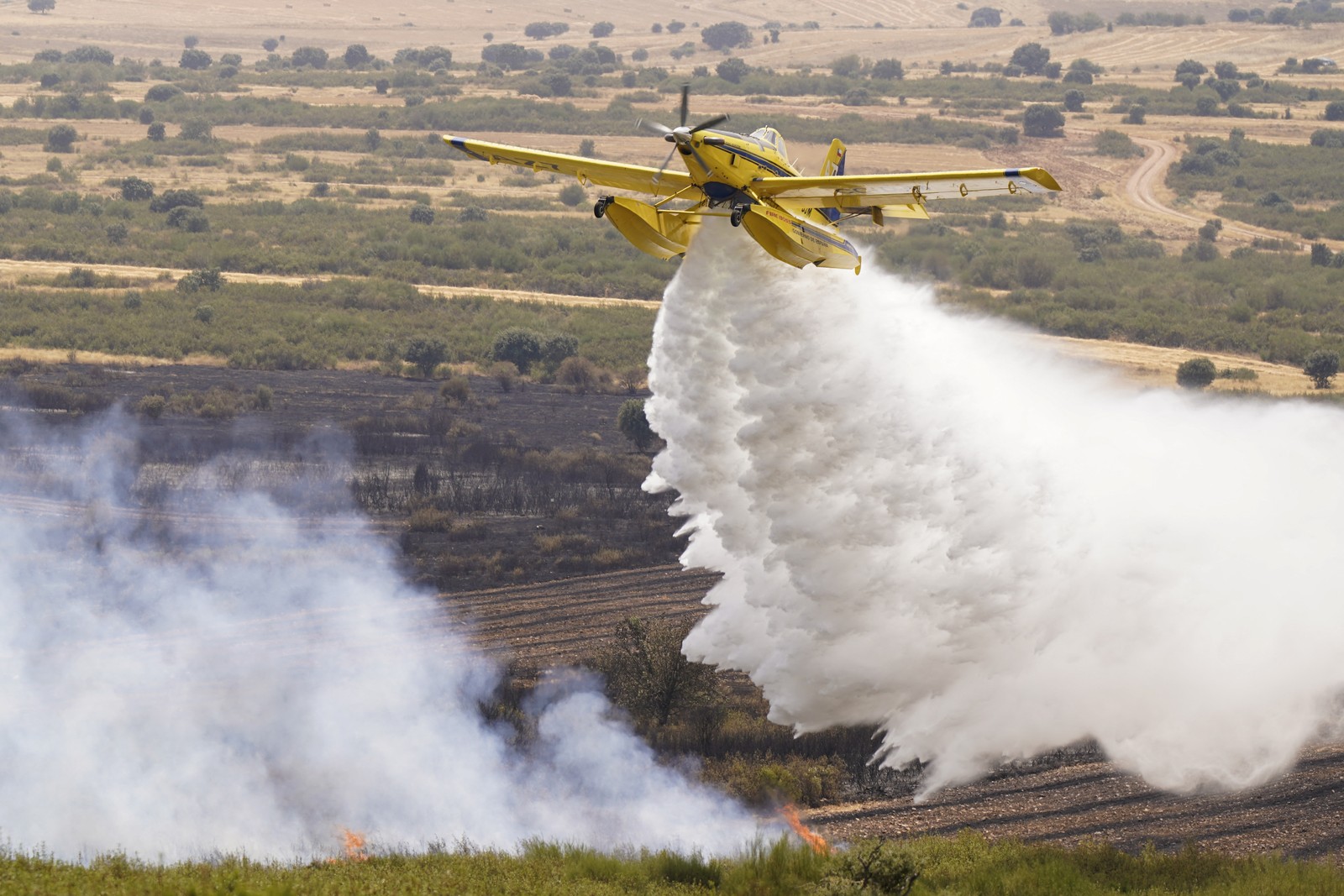 A small firefighting aircraft dumps water on a wildfire. 
