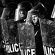 A black-and-white photo of a line of police officers with shields