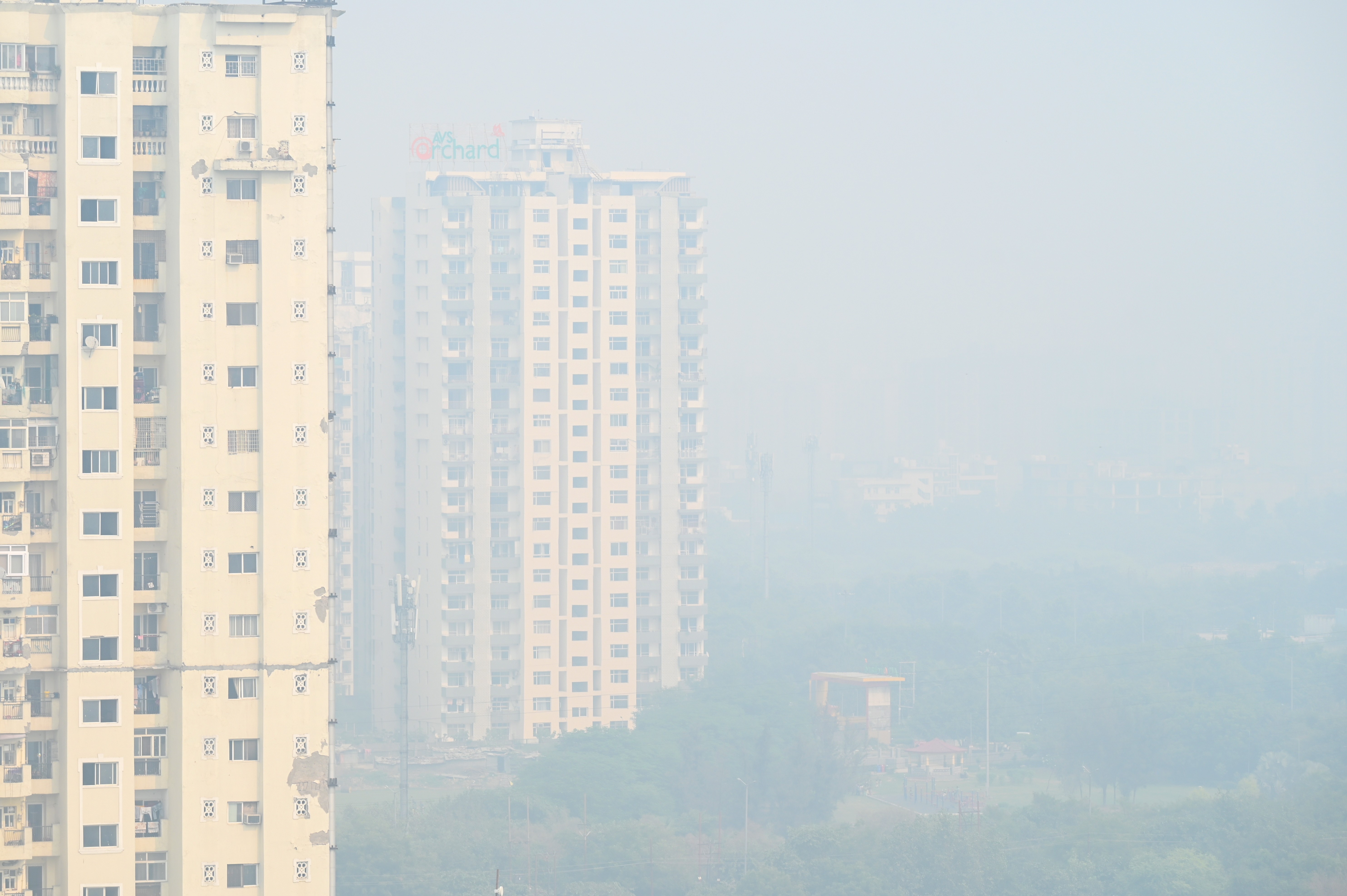 Smog fills the air among tall residential buildings.