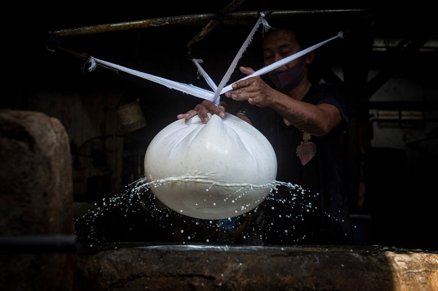 Liquid squirts from a cloth being spun in the tofu-making process.