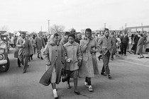 The black and white photos features four black students walking together as white students look on.