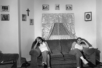 black-and-white photo of two women sitting at opposite ends of sofa in living room