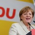 German Chancellor Angela Merkel gives a speech with her party's sign in the background.