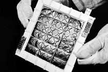 gloved hands hold a thermoelectric panel in a black and white photo