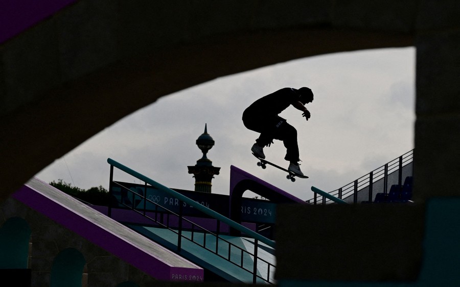 A skateboarder makes a jump above a railing at a skate park.