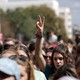 People raise their hands in peace signs at a rally. 