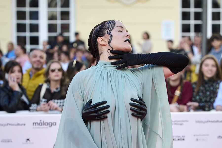 A person poses for photographers, wearing a garment with hands attached to the chest.