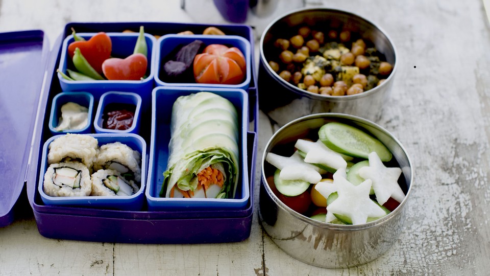 A lunch box filled with sushi and vegetables. 