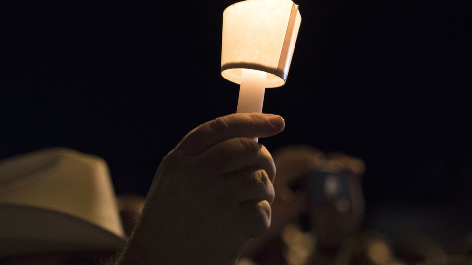 A hand holding a candle at a nighttime vigil