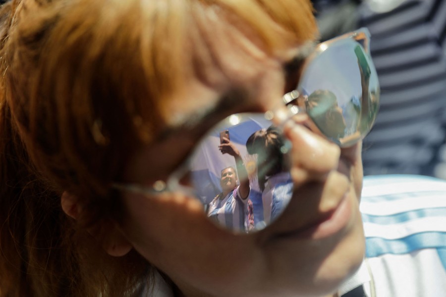 Soccer fans are seen reflected in the sunglasses of another fan.