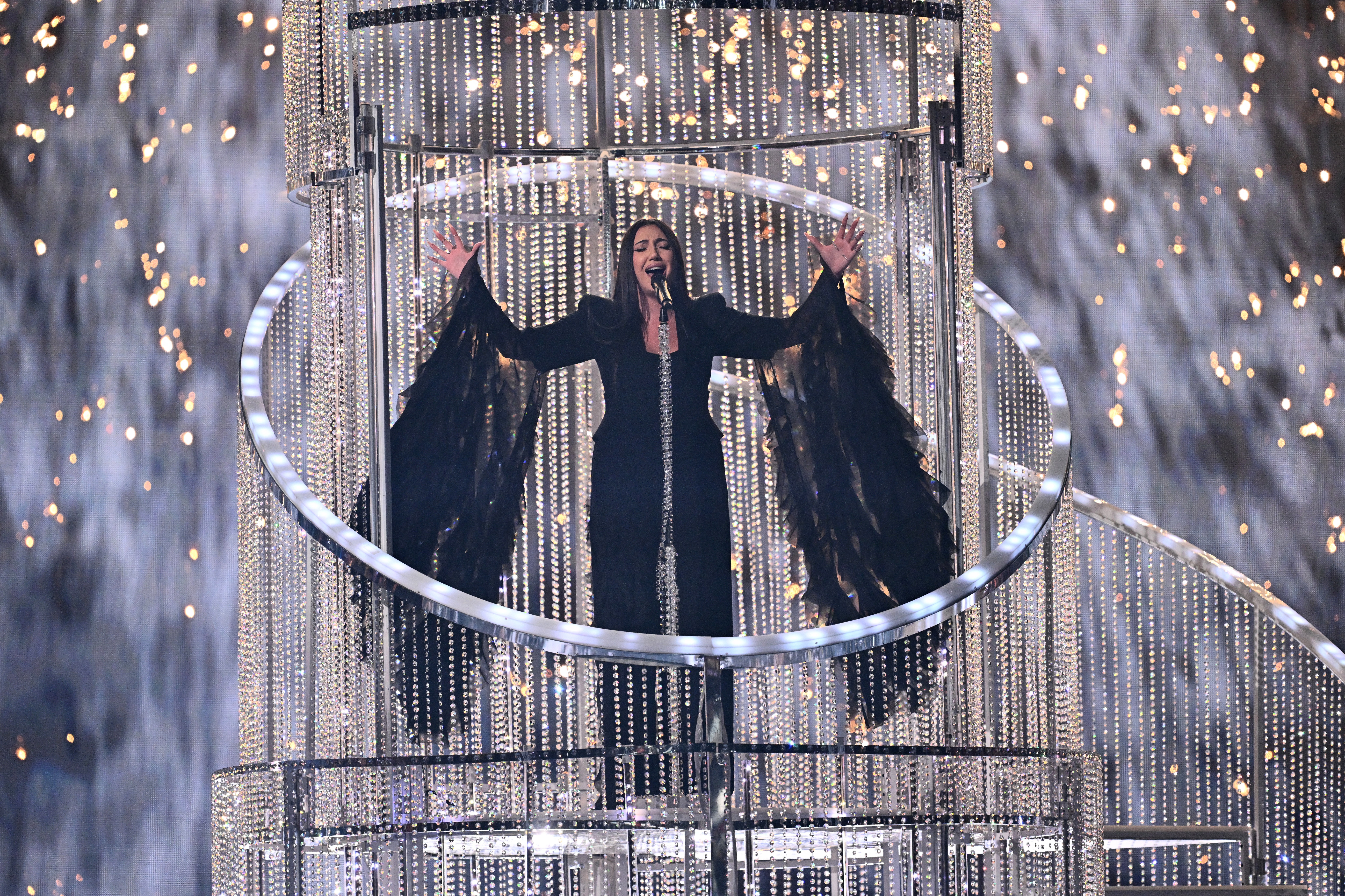A singer performs on stage, standing on a glowing platform.